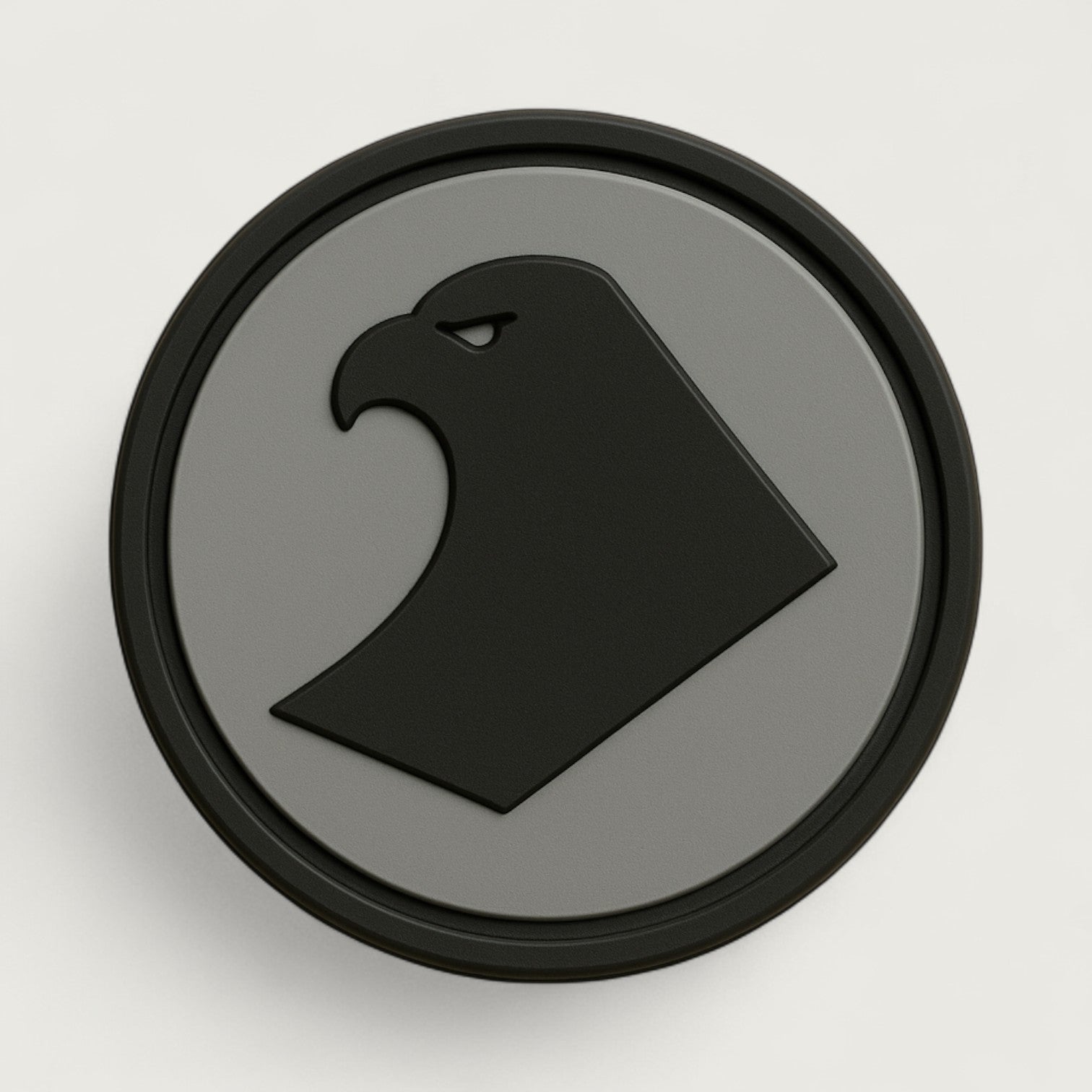 Round PVC patch with minimalist black eagle head logo on a gray background – tactical emblem patch for military, outdoor, or survival gear