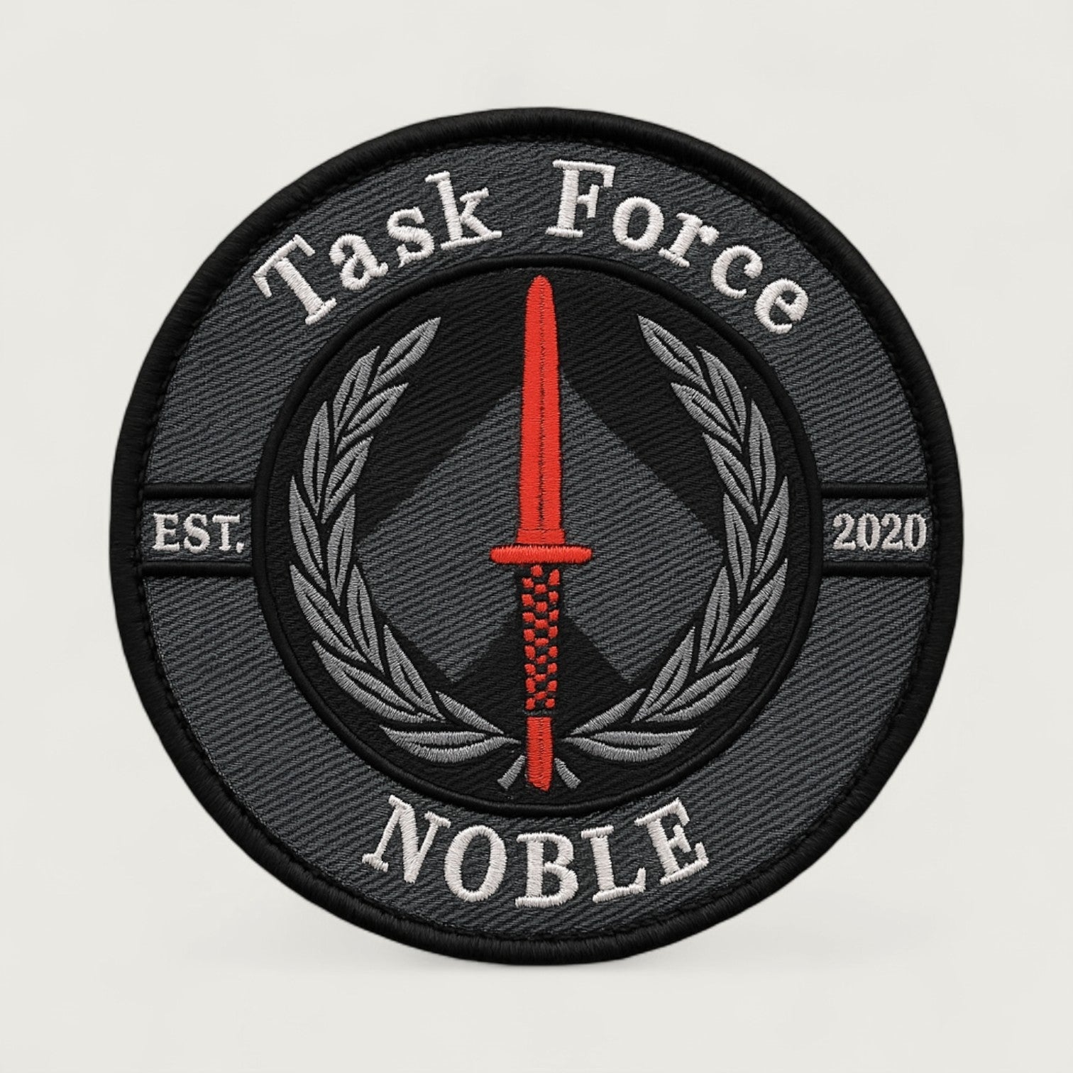 Round embroidered patch with gray and black background featuring a red tactical dagger, laurel wreath, and text 'Task Force Noble – EST. 2020' – custom military-style insignia patch