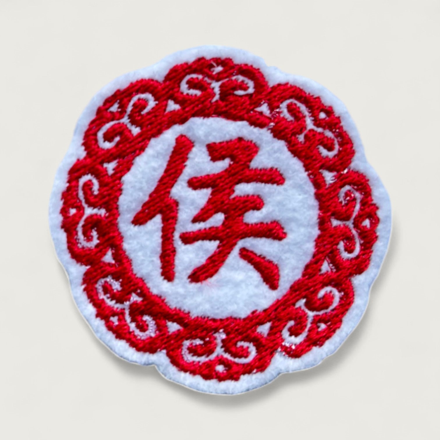 Circular embroidered patch with the red Chinese character “侯” (surname Hou) on white fabric, framed by a decorative red lace-style border. Ideal for personalized gifts, cultural accessories, or traditional attire.