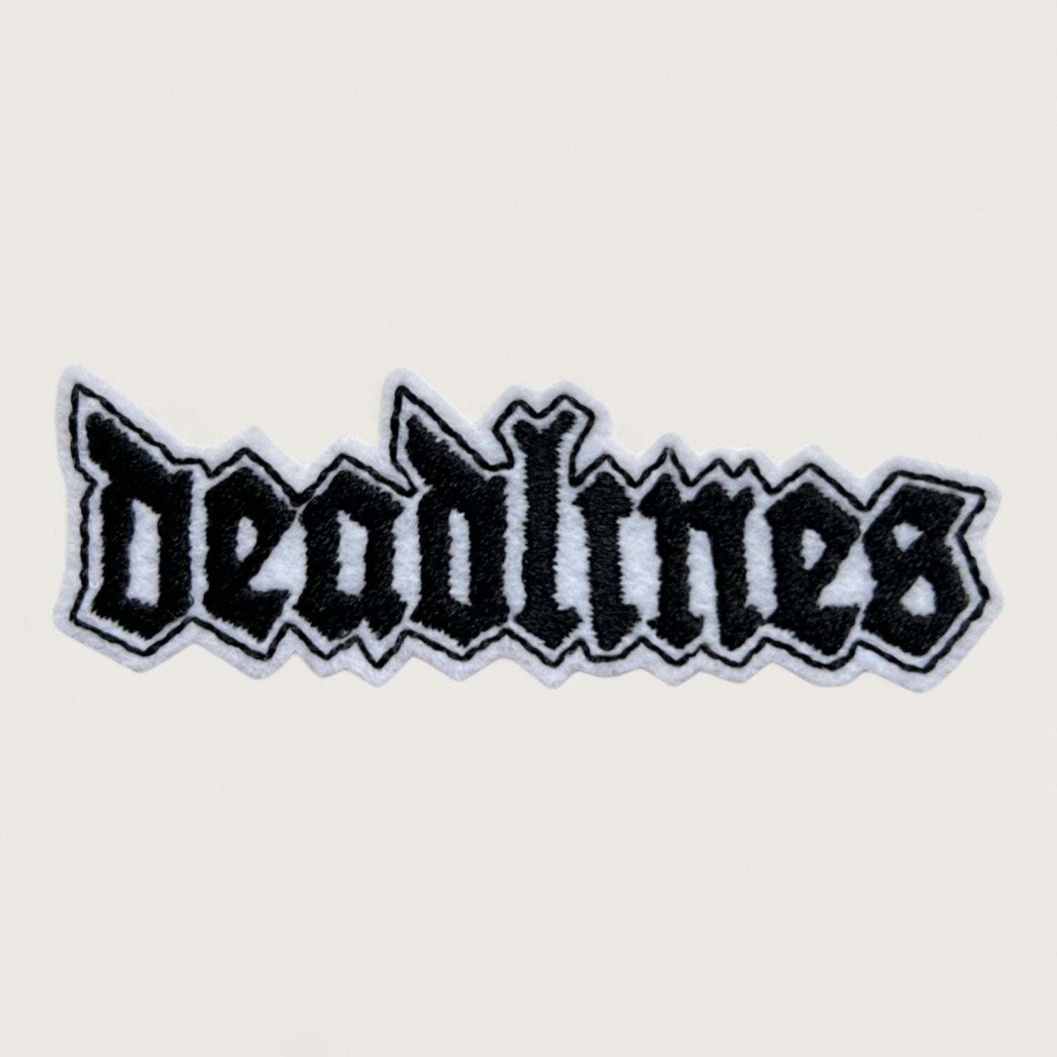 Black and white embroidered patch with the word 'deadlines' in gothic heavy metal-style font – edgy custom patch for students, creatives, and burnout humor.
