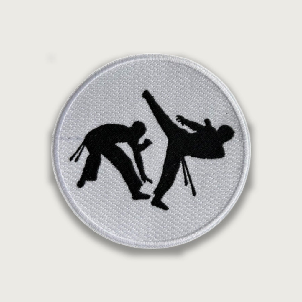 Round embroidered patch featuring black silhouettes of two martial artists sparring, one delivering a high kick