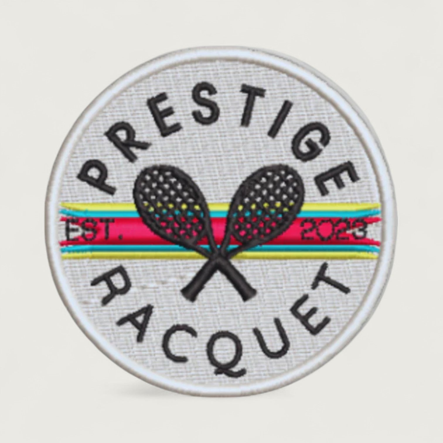 Prestige Racquet Club embroidered patch featuring two crossed tennis racquets over retro stripes and 'EST. 2023' text in a round white desig